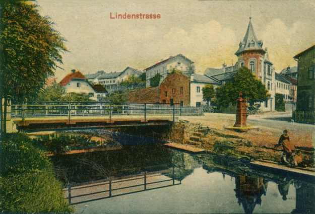 Ansicht der Kreuzung Passauer Straße, Bachstraße und Lindenstraße am Simbach mit Sedansbrunnen, um 1905